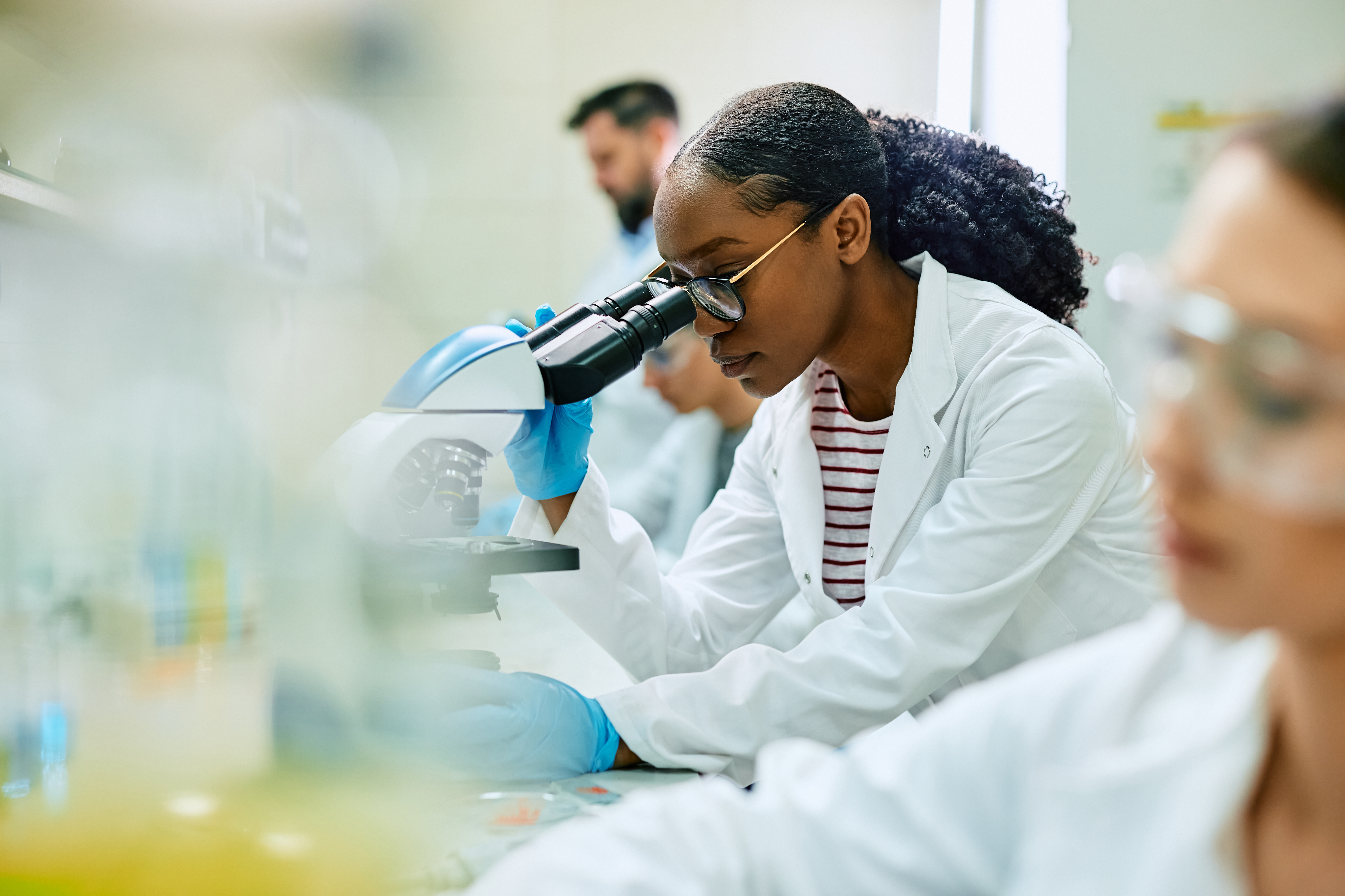 A scientist at a microscope reviewing a sample